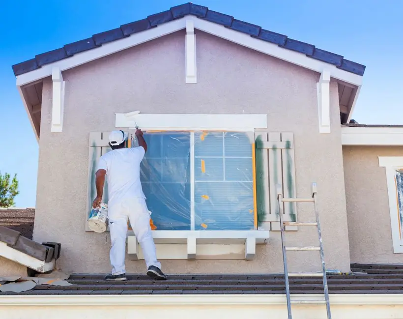 A man painting the outside of a house.