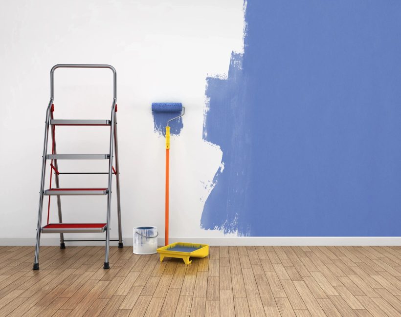 A ladder, paint brush and roller in front of the wall.