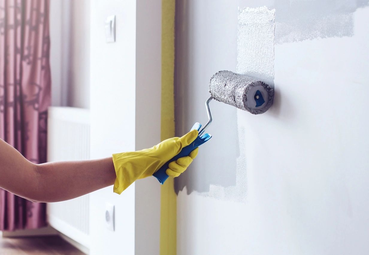 A person in yellow gloves painting the wall.